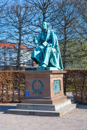 The statue of Hans Christian Andersen stands in Rosenborg Castle Gardens, Copenhagen, surrounded by trimmed hedges and trees. Visitors can enjoy the serene atmosphere and scenic views.の写真素材