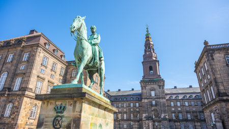 The equestrian statue of Christian IX stands majestically outside Christiansborg Palace, under a clear blue sky. Historic architecture frames the stately figure, symbolizing Danish heritage.の写真素材