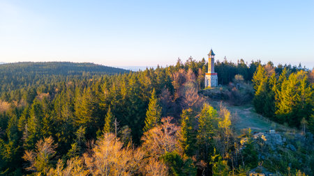 Stepanka Lookout Tower rises majestically in the Jizera Mountains during a serene spring morning. The surrounding forest reveals fresh greenery, inviting nature lovers to explore the area.の写真素材