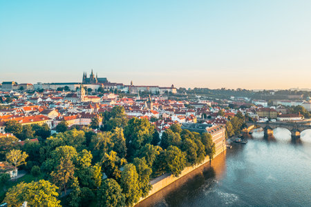 Prague awakens with the golden hues of sunrise illuminating the medieval architecture. The Vltava River reflects the breathtaking view of the city, including the iconic Charles Bridge and castle.の写真素材