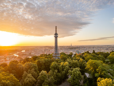 At sunrise, the Petrin Lookout Tower glows in golden light surrounded by lush greenery. This iconic structure offers breathtaking views of Prague from its elevated position.の写真素材