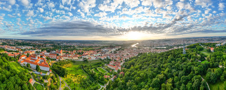 A breathtaking sunrise illuminates the sky above Prague, highlighting the Vltava River and Prague Castle. The lush greenery of Petrin Hill contrasts beautifully with the vibrant cityscape.の写真素材