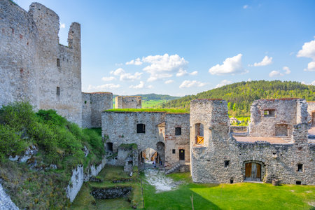 Visitors wander through the scenic courtyard of Rabi Castle, enjoying stunning stone architecture under a bright sky. Surrounding nature complements this historical site, inviting exploration.の写真素材