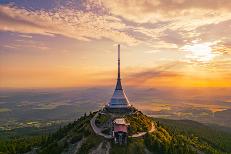 Jested Mountain Hotel stands tall at sunset, showcasing modern architecture and a unique silhouette against the colorful sky. Visitors enjoy stunning panoramic views of the surrounding landscape.の写真素材