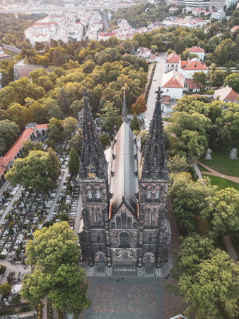 The stunning Vysehrad Basilica of St. Peter and St. Paul stands majestically at sunrise, surrounded by lush greenery and historic buildings in Prague, Czechia.の写真素材