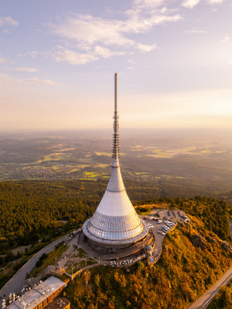 The Jested Mountain structure stands prominently on Jested peak in Liberec during a vibrant sunset. The modern architecture contrasts beautifully with the surrounding landscape under clear skies.の写真素材