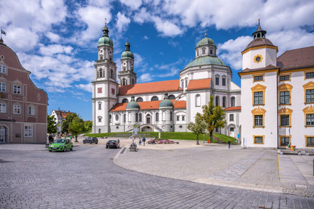 St. Lorenz Basilica stands majestically in Kempten, Bavaria, showcasing baroque architecture against a vivid sky. Visitors explore the area around the basilica and admire its intricate details.の写真素材