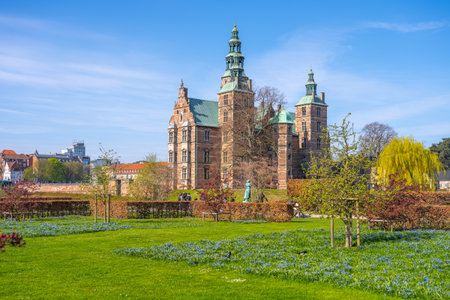 Rosenborg Castle in Copenhagen is surrounded by vibrant gardens and blooming flowers, showcasing Renaissance architecture against a clear blue sky in the joy of spring.の写真素材