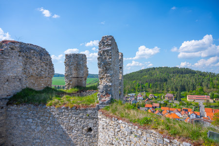 Rabi Castle stands majestically against a backdrop of lush greenery and a quaint village, showcasing the remnants of its fortifications under a clear blue sky.の写真素材
