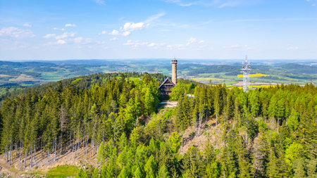 Aerial view captures the impressive Svatobor lookout tower nestled among lush green forests in Czechia, showcasing the towers scenic surroundings and distant landscape.の写真素材