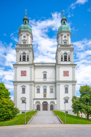 St. Lorenz Basilica, a stunning baroque structure in Kempten, Bavaria, showcases its grandeur with ornate towers and vibrant designs against a bright blue sky.の写真素材