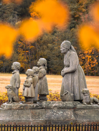 In Granny Valley, Ratiborice, a statue depicts a grandmother standing with her grandchildren. The scene showcases autumn foliage, celebrating Czech culture and Bozena Nemcovas legacy.の写真素材
