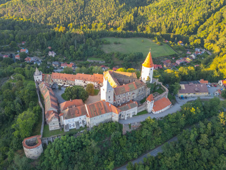 Krivoklat Castle stands majestically amid lush greenery, captured from above during a beautiful sunset. This medieval structure showcases rich history and stunning architecture in Central Bohemia.の写真素材