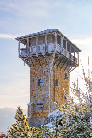 A scenic lookout tower stands on Wysoki Kamien in the Jizera Mountains, surrounded by snow-covered trees. The sky is clear, offering a perfect view of the winter landscape.の写真素材