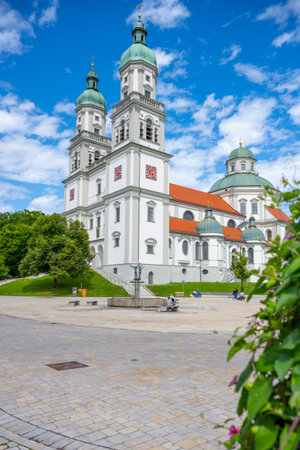 St. Lorenz Basilica stands majestically in Kempten, Bavaria, showcasing its baroque architecture under a bright blue sky. Visitors admire the historic structure surrounded by greenery.の写真素材