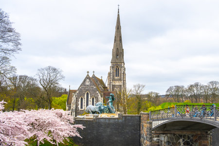 St Albans Church stands tall near Kastellet in Copenhagen, showcasing its striking architecture amidst blooming cherry blossoms. Visitors can admire this serene spot in springtime.の写真素材