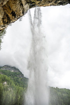 Water cascades dramatically from Johannes Waterfall, surrounded by lush greenery near Obertauern, Austria. The mist rises, creating an awe-inspiring atmosphere in the Alps.の写真素材
