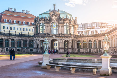 Visitors walk around the Zwinger Palace in Dresden, Germany. The majestic buildings stand tall under the winter sun as people enjoy the festive atmosphere during Christmas time.の写真素材