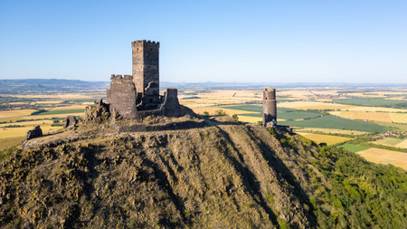 Hazmburk castle ruins stand proudly atop a hill, offering breathtaking views of the Central Bohemian Uplands. This medieval fortress showcases rich history amid the serene landscape of Czechia.の写真素材