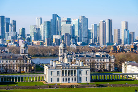 A stunning view from Greenwich Park shows historical buildings surrounded by lush greenery,...