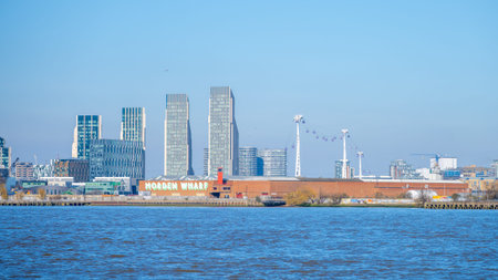 A view of Modern Wharf in Greenwich, London, shows the buildings and structures along the river. The background highlights the skyline and sky. Boats are present on the water.の写真素材