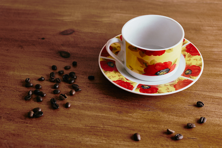white circles with red flowers standing on a wooden table, scattered coffee beansの写真素材