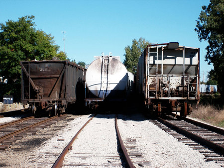 A photo showing three train cars from behind, each a different type of car including a coal carrier,...