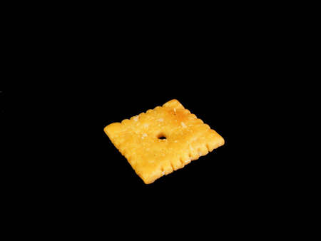A cheese cracker against a black background.の写真素材