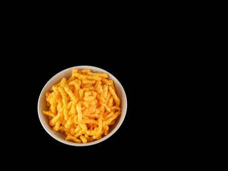 A bowl of cheese snacks against a black background.の写真素材