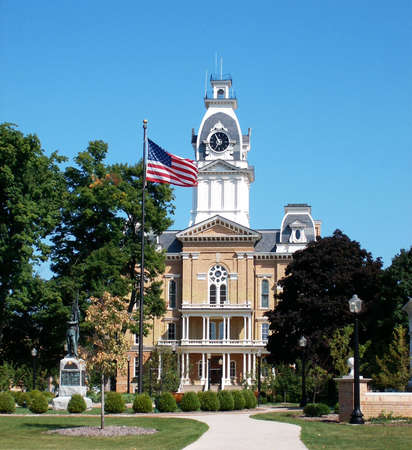 A Victorian building with a clock tower and a U.S. flag waving in the front.の写真素材
