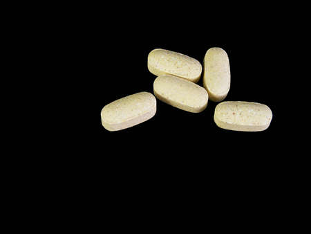 Over-the-counter caplets against a black background.の写真素材