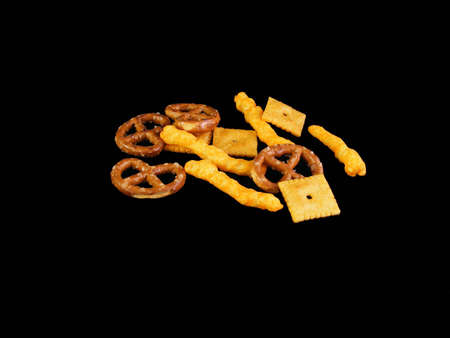Cheese snacks, pretzels and cheese crackers against a black background.の写真素材