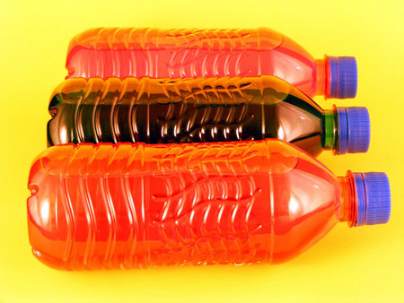 Three sports drinks in plastic bottles against a yellow background.