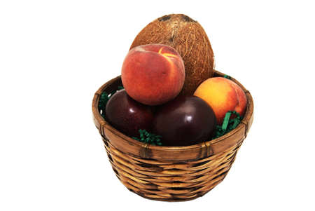 A fruit basket containing plums, peaches and a coconut.の写真素材