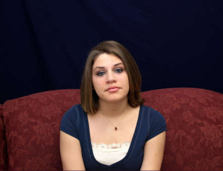 A pretty young brunette teenager on a sofa.の写真素材