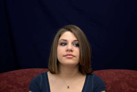 A pretty young brunette teenager on a sofa.の写真素材