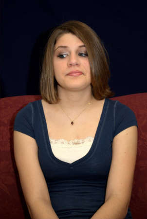 A pretty young brunette teenager on a sofa.の写真素材