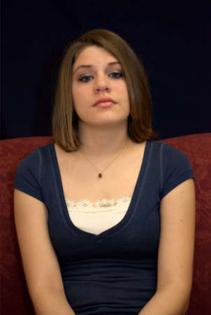 A pretty young brunette teenager on a sofa.の写真素材