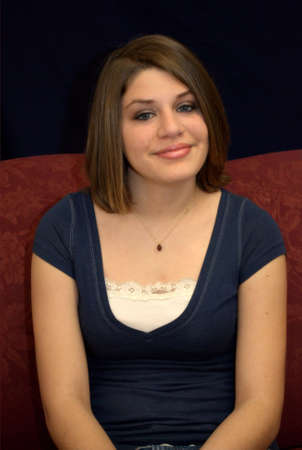 A pretty young brunette teenager on a sofa.の写真素材