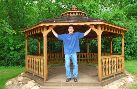 A young man standing in a wooden gazebo.の写真素材