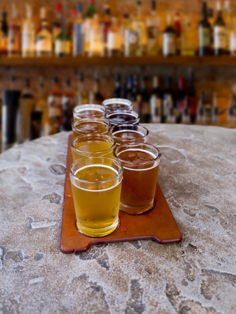 beer flight of eight sampling glasses on a serving paddle in a barの写真素材