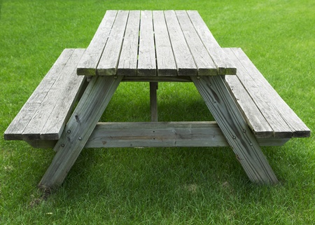 wooden picnic table with benches on a green grass lawnの写真素材
