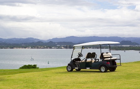 parked golf cart facing water reservoir with dramatic cloudy skyの写真素材