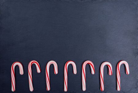 Seven holiday striped candy canes on dark background. Top view, flat lay.の写真素材