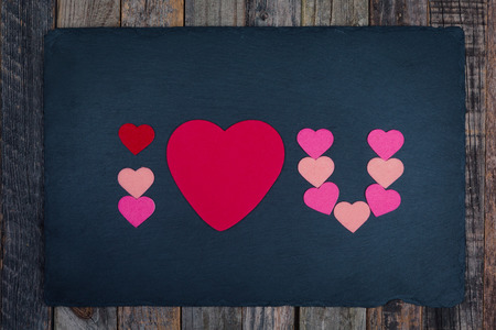 Abbreviated text I Love You with a heart shape on dark background over wood. Flat lay, top view.の写真素材