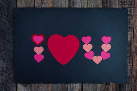 Abbreviated text I Love You with a heart shape on dark background over wood. Flat lay, top view.の写真素材