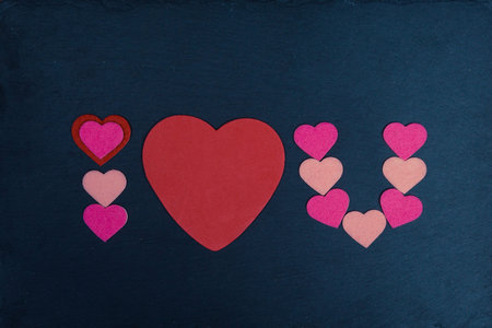 Abbreviated text I Love You with heart shape on chalkboard over vintage wood. Flat lay, top view.