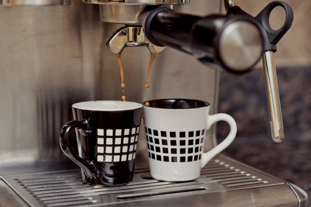 Home espresso machine on kitchen countertop making two cups coffee.の写真素材