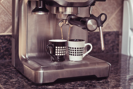 Home espresso machine on kitchen countertop making two cups coffee.の写真素材