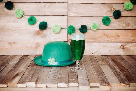 Glass of green beer with Irish festive hat on wooden background. Tabletop, side view.の写真素材